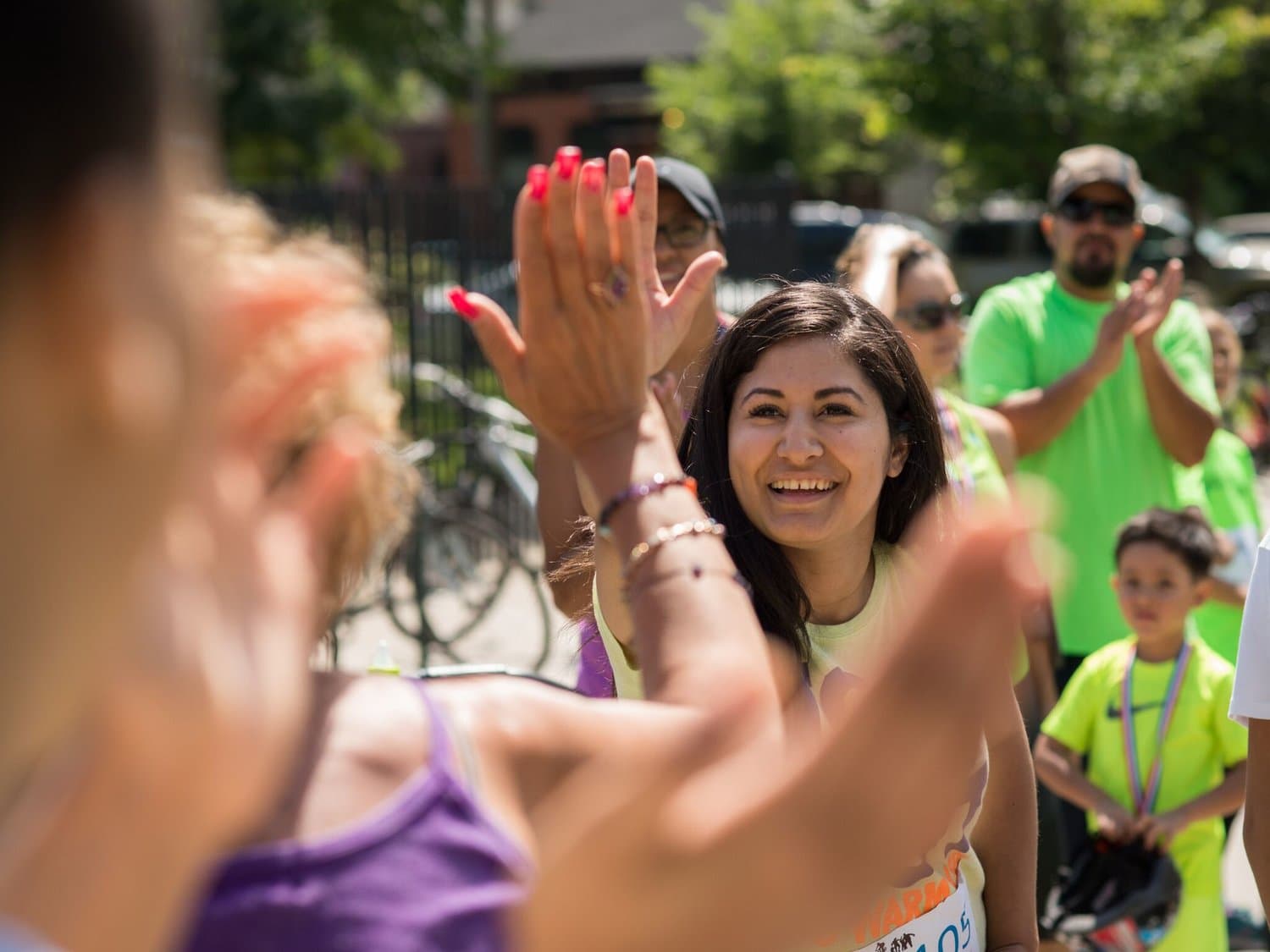 A smiling ViVe coach high-fives a child while other kids and parents look on
